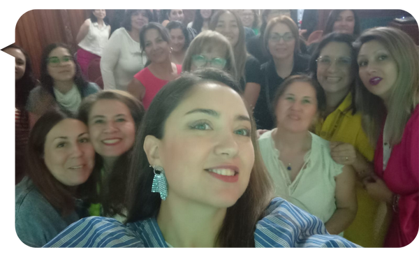 Bárbara Contreras sonríe mientras toma una selfie en un evento rodeada de mujeres que también posan alegremente para la cámara.