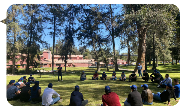 Julián Mendiola facilitando una actividad grupal en un entorno al aire libre, con participantes sentados en círculo durante una jornada de formación en liderazgo.