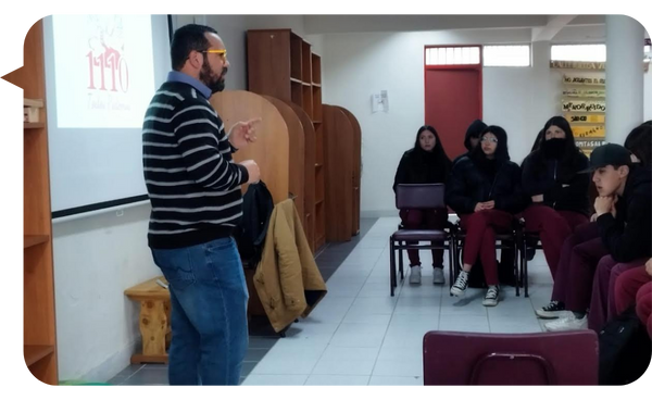 Óscar Alarcón impartiendo una charla sobre prevención de adicciones a un grupo de jóvenes en un salón educativo.