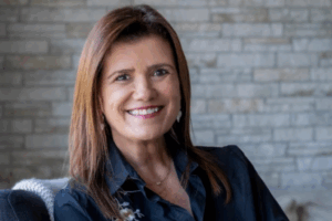 Pilar Sordo sonriendo en primer plano, con fondo de muro de piedra gris.